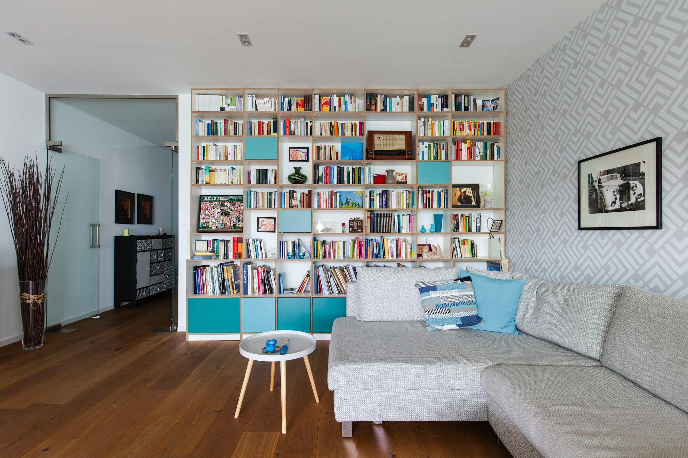 Wohnzimmer mit wandfüllendem Bücherregal und Sofa