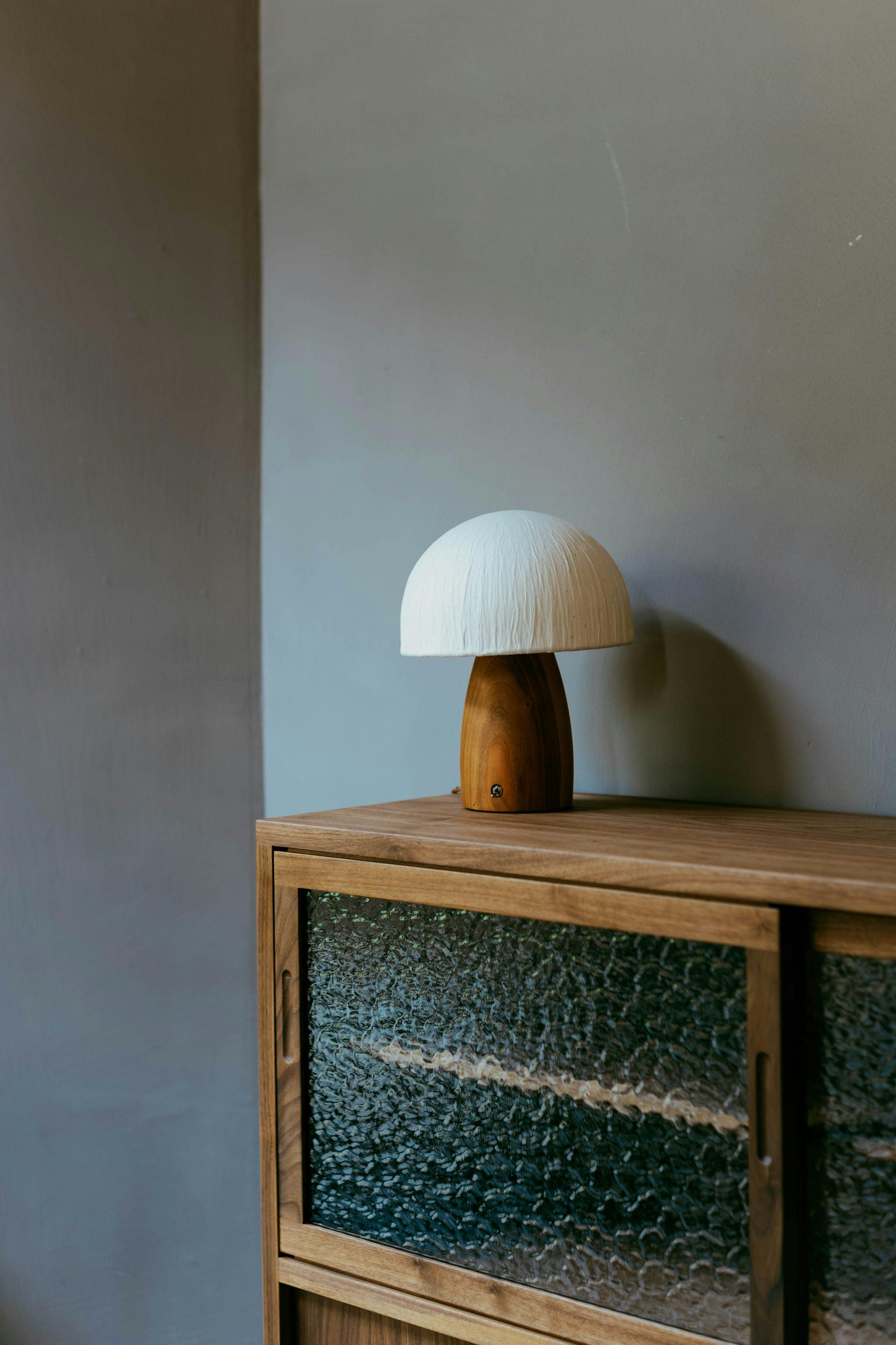 Sideboard Hafen aus Nussbaum mit Pilzleuchte vor einer grauen Wand